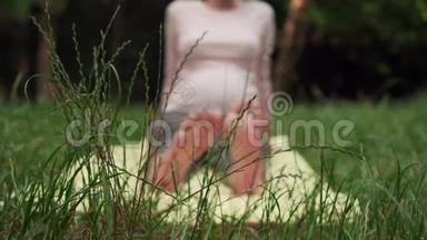 孕妇在公园里用地毯做瑜伽，双腿伸直，做脚的热身。